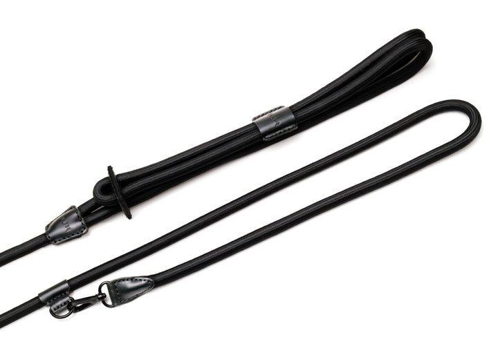Black rope dog harness with black leather and metal details that includes a hands-free clip. 