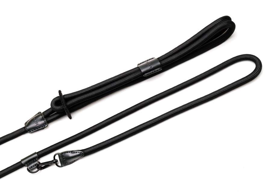 Black rope dog harness with black leather and metal details that includes a hands-free clip. 